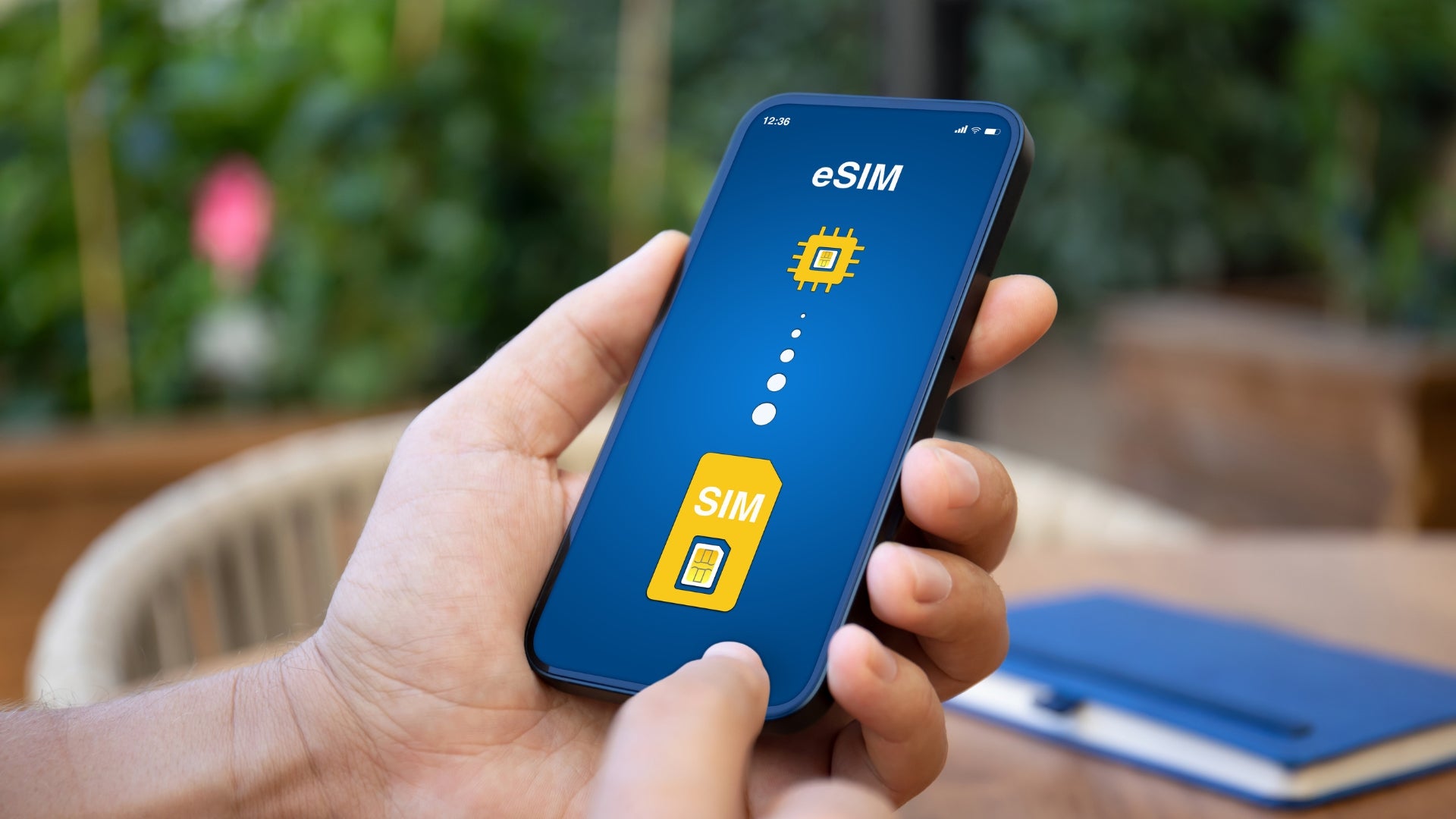 Hand holding a smartphone with eSIM and SIM card icons displayed on the screen.