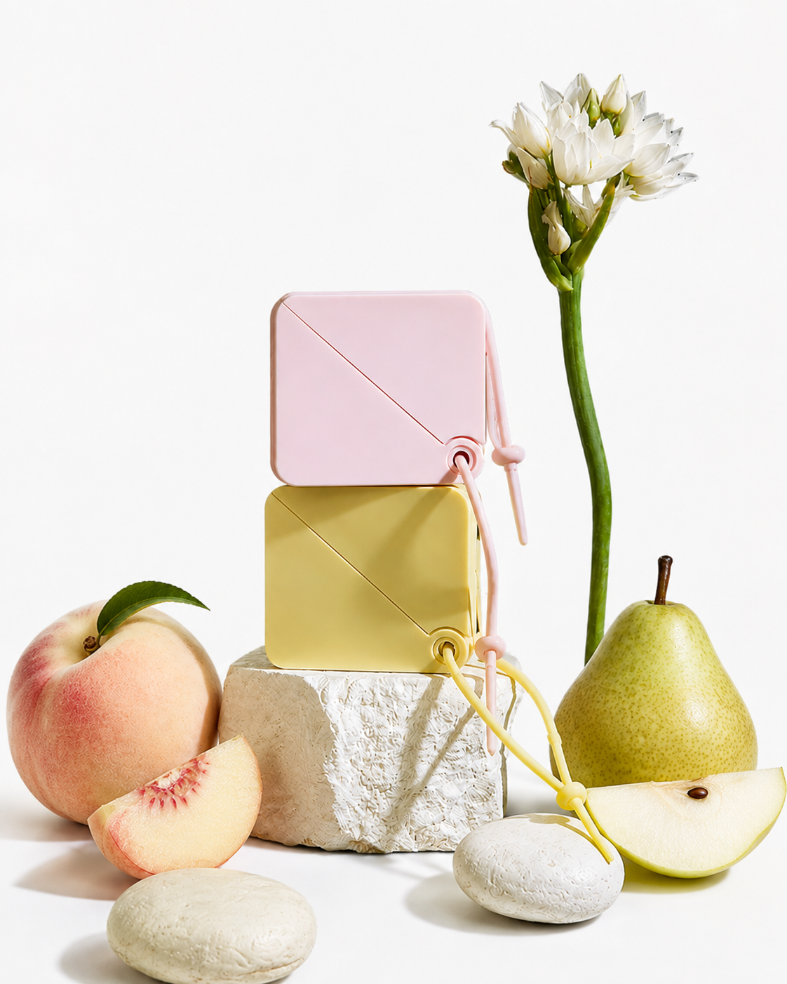 Pink and yellow portable paper soap sheets with peach and pear scents displayed beside fresh fruit, compact travel hand soap for camping, hiking, travel, and everyday hygiene.