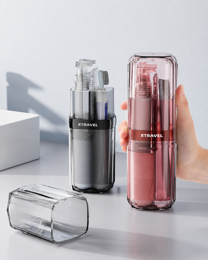 A hand holds a translucent pink travel-sized toothbrush holder with visible toothbrushes inside, while another empty translucent holder lies on its side in the foreground. A third empty holder stands behind the first.