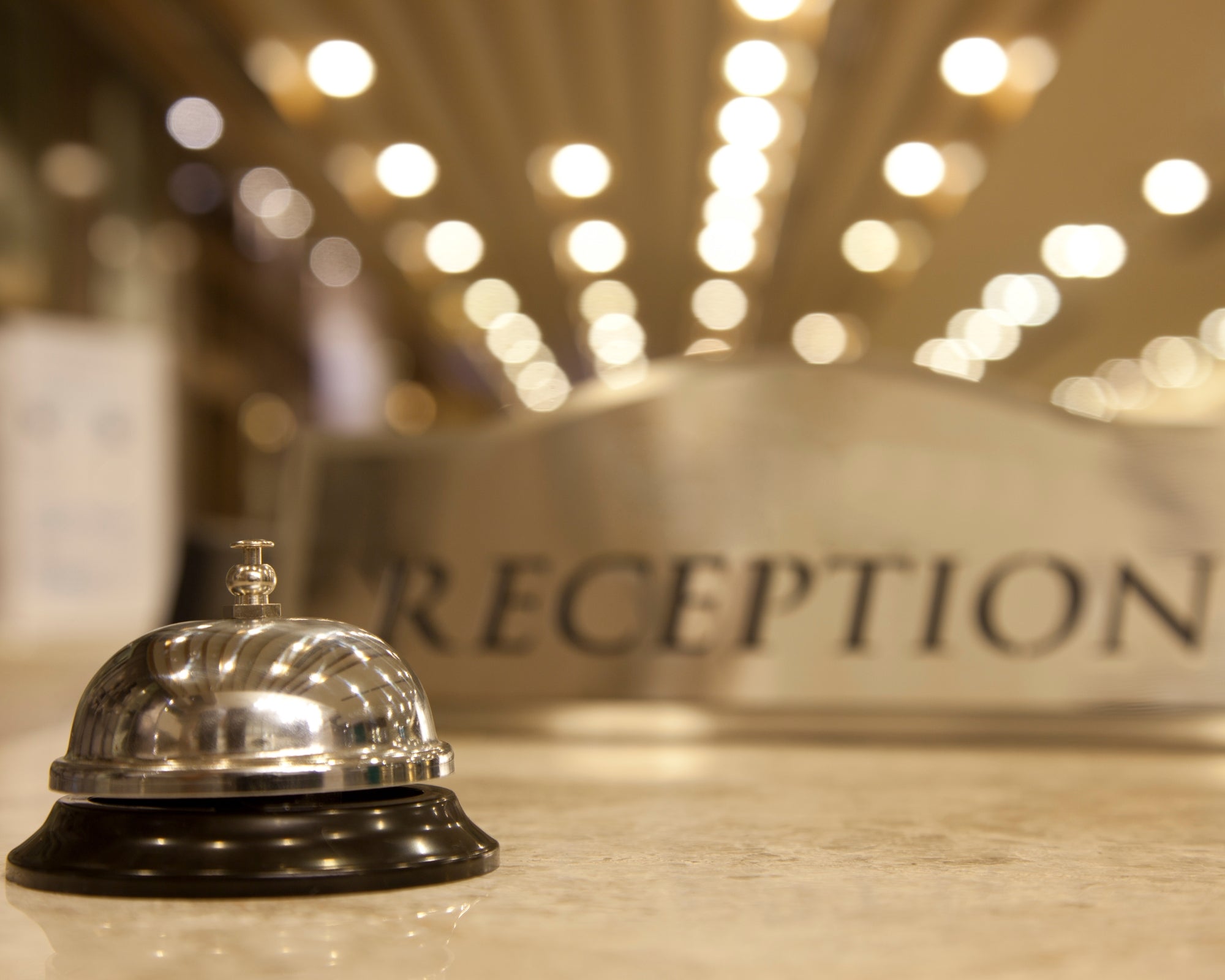 Silver reception bell on a desk with 'RECEPTION' sign in the background